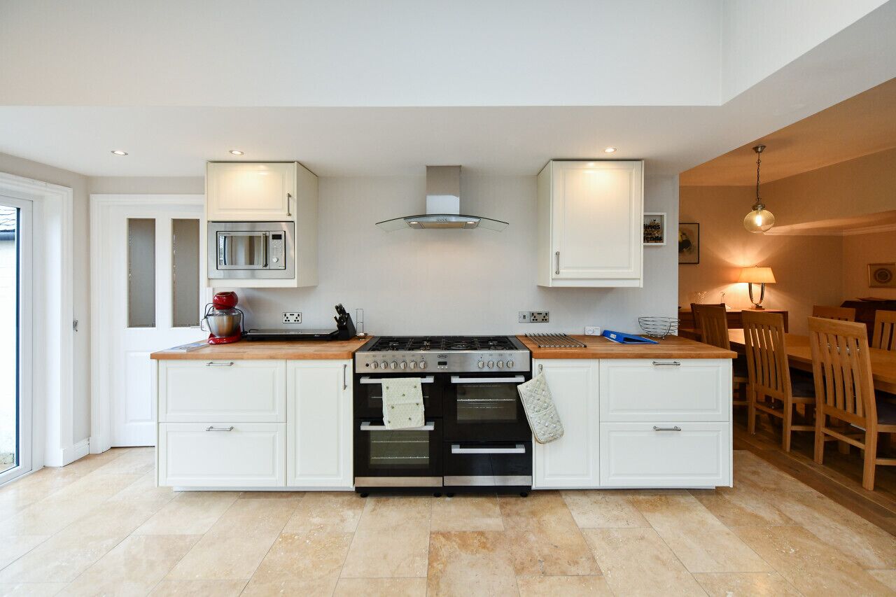 A modern kitchen with white cabinetry, a built-in oven, a microwave, and a gas stove.