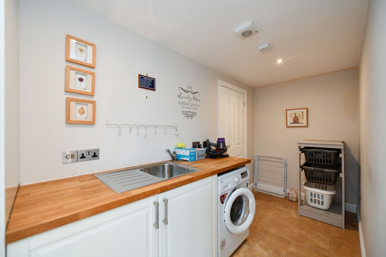 A laundry room with a washing machine, a drying rack, and a shelf with laundry baskets.