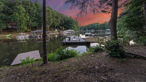 A lakeside dock with boats, a gazebo, and a house in the background. - Lakefront Retreat with Private Dock, Pool, Game Room | Sleeps 18 (Mooresville)