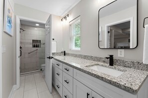 A modern bathroom with a walk-in shower, a large mirror, and a granite countertop. - Lakefront Retreat with Private Dock, Pool, Game Room | Sleeps 18 (Mooresville)