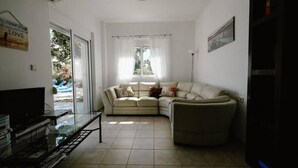 A living room with a beige sofa, a glass coffee table, and a television on a stand. - Villa Maia in Rhodes (Rhodes)