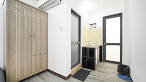 Una habitación pequeña con armario, lavamanos y puerta que da a otra zona.