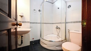 Un baño con ducha envuelta en vidrio, lavamanos e inodoro.