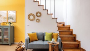 Ein Wohnzimmer mit grauem Sofa, einer Holztreppe und einem grünen Schrank.