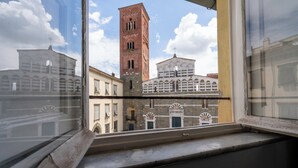 Blick aus einem Fenster auf ein historisches Gebäude mit einem markanten Turm und Rundbogenfenstern.