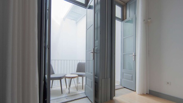 An open door leading to a balcony with two chairs and a small table.
