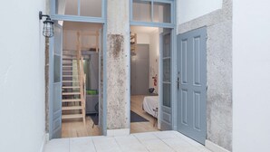 A narrow hallway with a wooden ladder leading to a loft bedroom, a bed, and a small seating area. - Studio with Mezzanine (Porto)