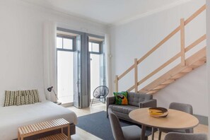 Une chambre d’hôtel moderne équipée d’un lit, d’un canapé, d’une table à manger et d’un escalier.