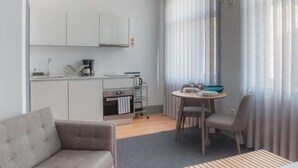 Ein kompakter Wohnbereich mit Küchenzeile, einem Essbereich mit Tisch und Stühlen sowie einer Couch.