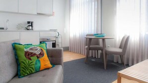 Ein modernes Wohnzimmer mit einem grauen Sofa, einem Holztisch und einem Essbereich mit einem kleinen Tisch und zwei Stühlen.