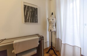 Um quarto com um manequim em um suporte, um quadro na parede e um radiador com um tecido listrado.