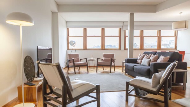 Un salón amplio con un ventanal grande, un sofá, dos sillones, una mesa de centro y una lámpara de pie.