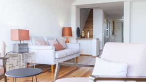 A modern living room with a white sofa, a round coffee table, and a wooden floor.