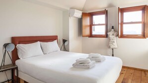 A bedroom with a bed, a mannequin, and two windows.