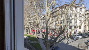 A street view with parked cars, trees, and buildings.