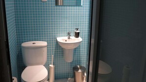 Un baño con inodoro, lavamanos y cubo de basura.