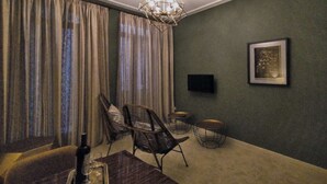 Una habitación con una mesa de comedor, dos sillas, una araña, un televisor y un cuadro en la pared.