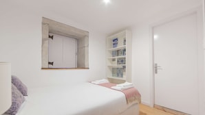 Una camera da letto con un letto, un armadio, uno scaffale con oggetti decorativi e una porta.