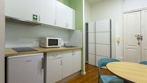 A compact kitchen with a microwave, refrigerator, and a small refrigerator. There is a table with chairs and a sink. - One-bedroom apartment with a sofa bed (Porto)