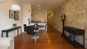 Ein modernes Wohnzimmer mit Steinwand, Kamin und Essbereich mit rundem Tisch und Stühlen.