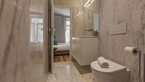 A modern bathroom with a toilet, sink, and shower area. - Suite with a double bed and air conditioning (Porto)