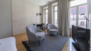 A modern hotel room with a large window, two armchairs, a small table, and a TV. - Suite with a view to the city, double bed and air conditioning (Porto)