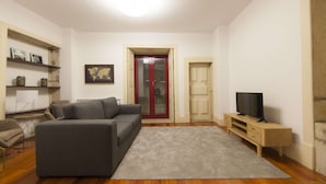 Una sala de estar con un sofá gris, un televisor sobre un mueble de madera y un mapa del mundo en la pared.