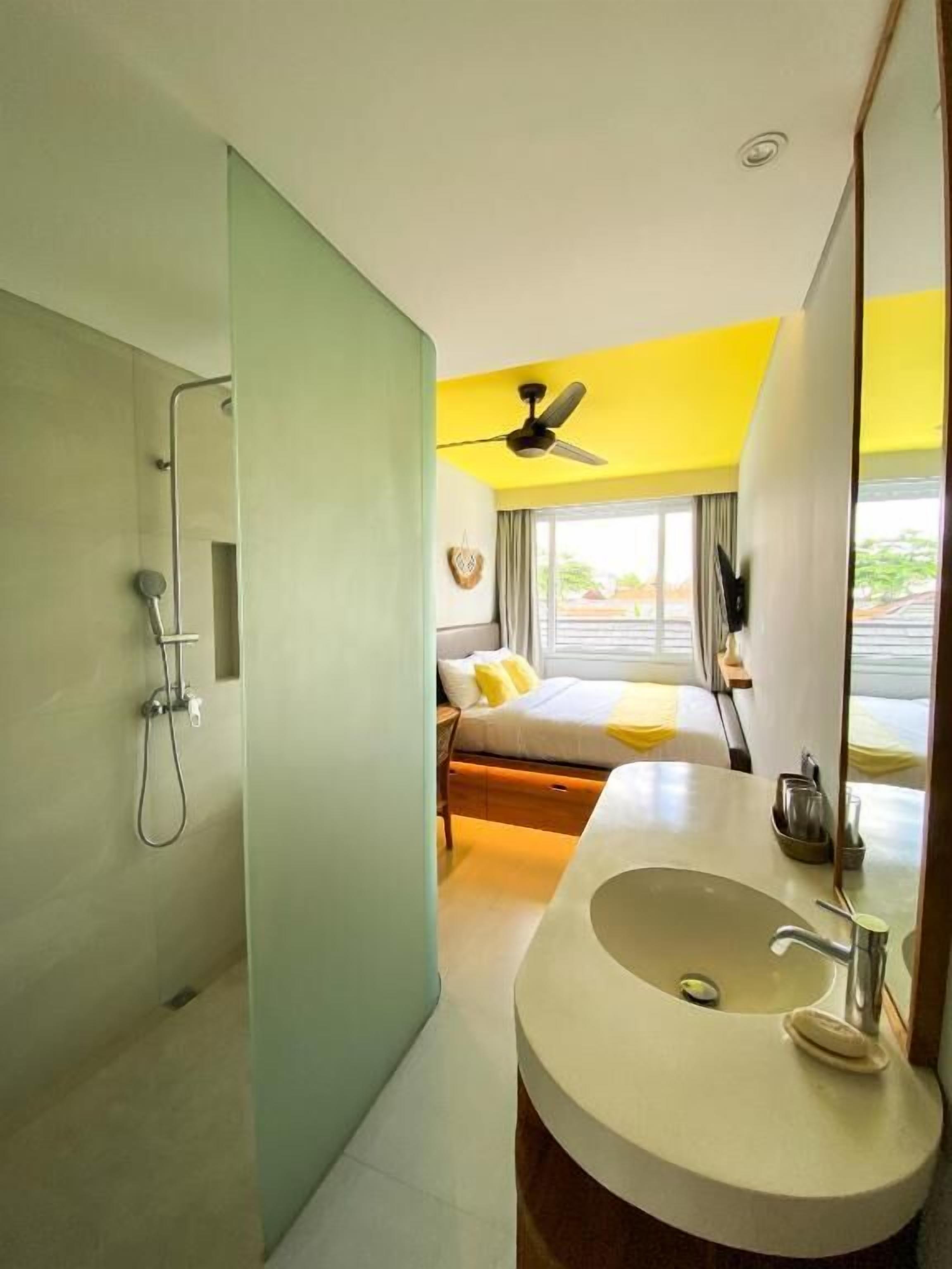 A modern bathroom with a shower, a sink, and a bed with a view.