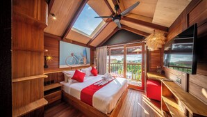 A wooden bedroom with a large bed, a ceiling fan, a TV, and a balcony with a view. - SOKKOOL CANGGU - COWORKING & COLIVING (Tibubeneng)