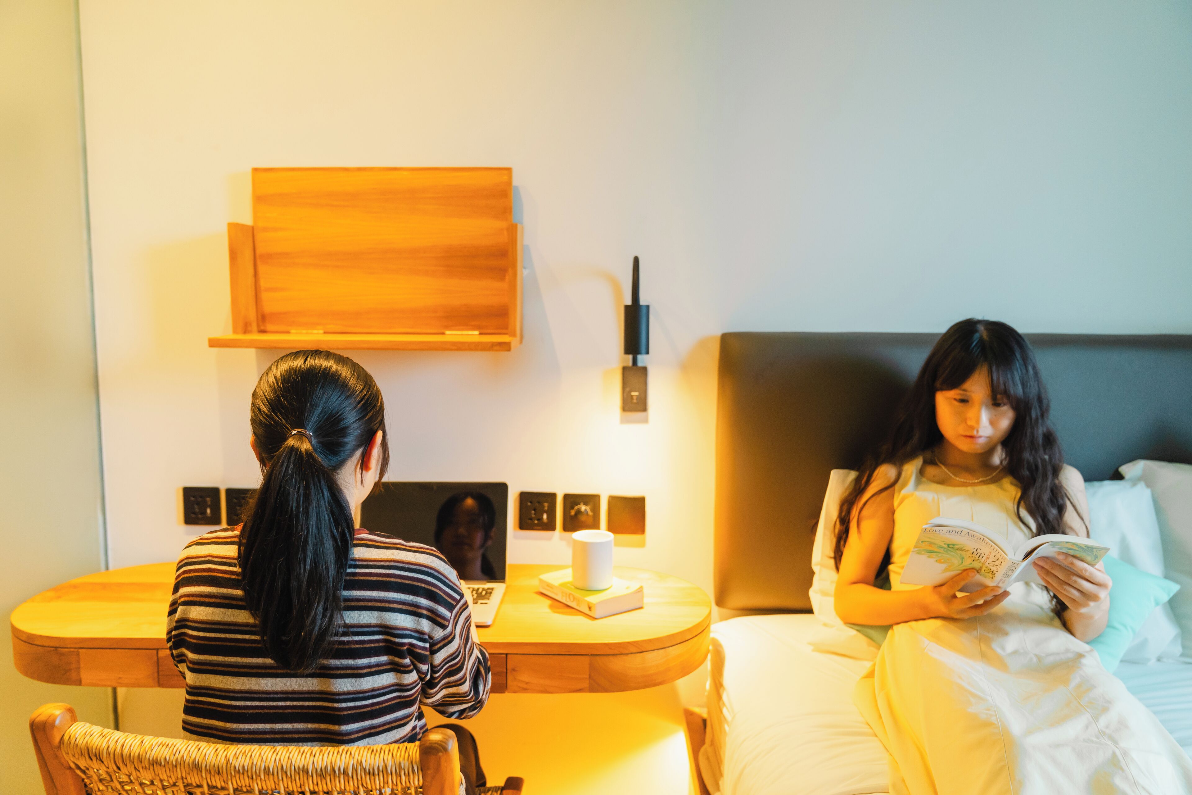 Une chambre d’hôtel avec un lit, une table de chevet avec une lampe, un ordinateur portable et une chaise.