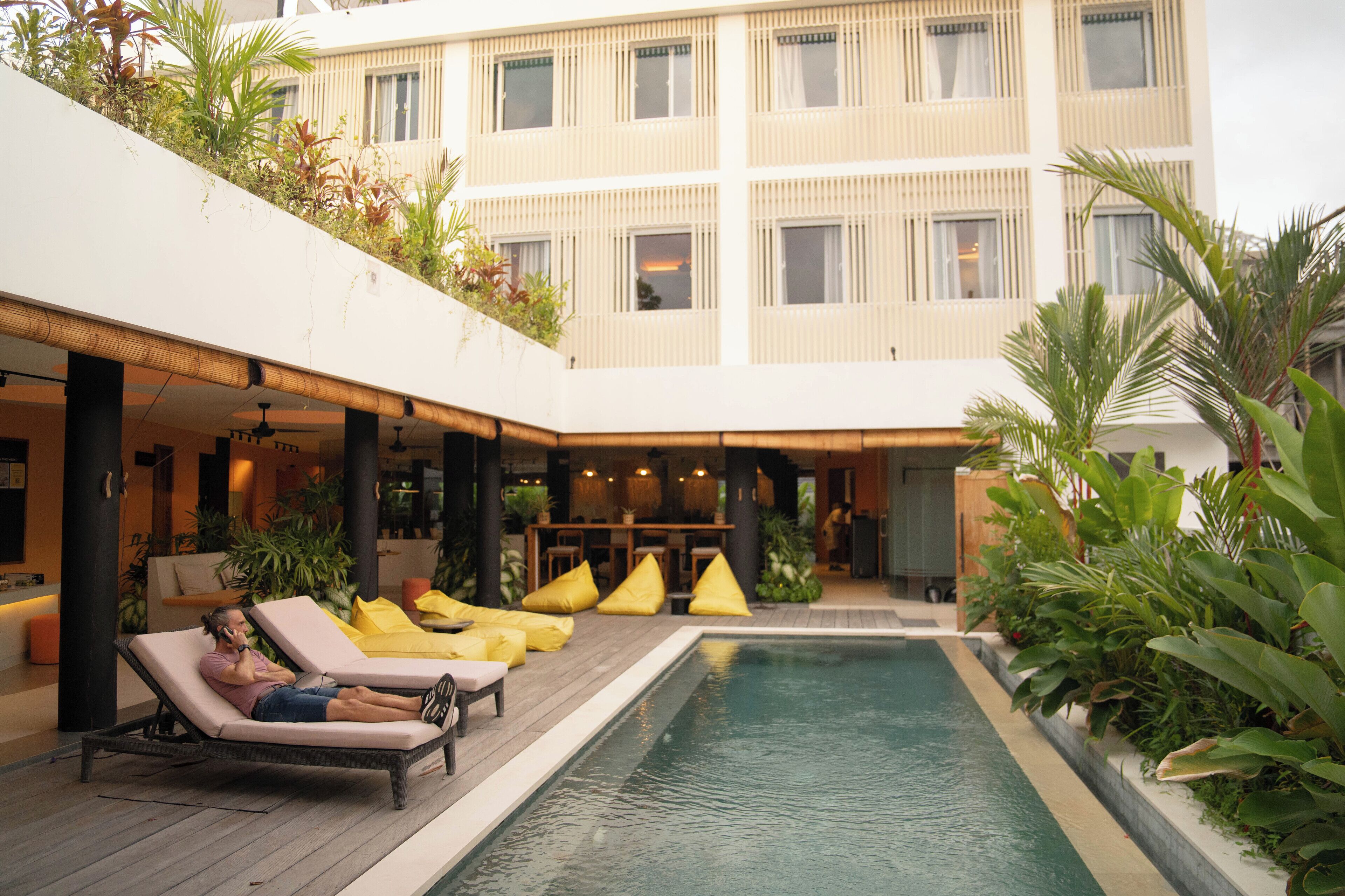 A pool area with lounge chairs and a person using a phone.