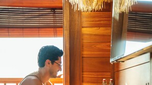 A person using a laptop at a wooden counter with a straw roof overhead. - SOKKOOL CANGGU - COWORKING & COLIVING (Tibubeneng)