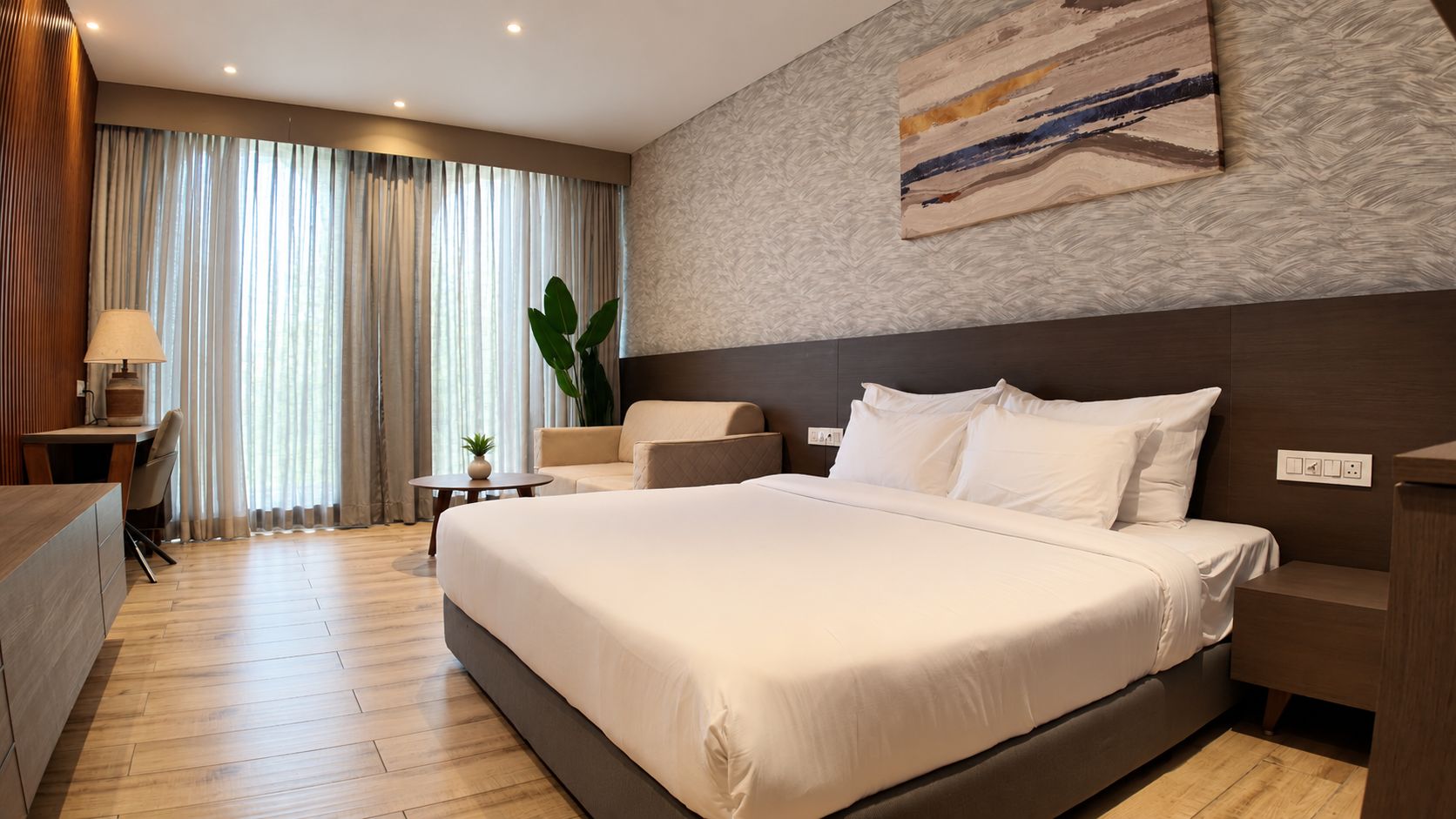 Una habitación de hotel con una cama grande, mesitas de noche, un escritorio y una silla.