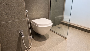 A modern bathroom with a toilet, shower, and glass enclosure. - THE DEMOCRACY HOTEL & RESORT (Nashik)