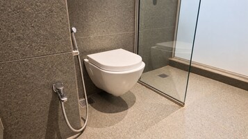 Un baño moderno con inodoro, ducha y mampara de vidrio.