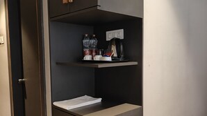 A kitchenette with a coffee maker, water bottles, and a small shelf. - THE DEMOCRACY HOTEL & RESORT (Nashik)