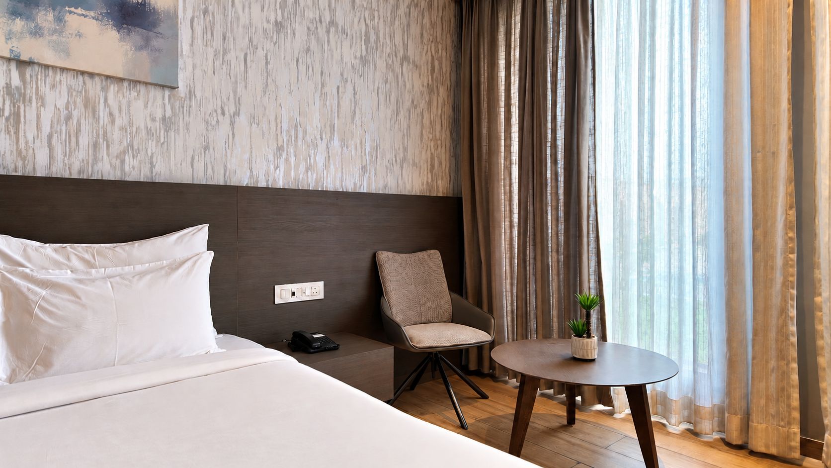 Una habitación de hotel con una cama, una silla, una mesita y una planta.