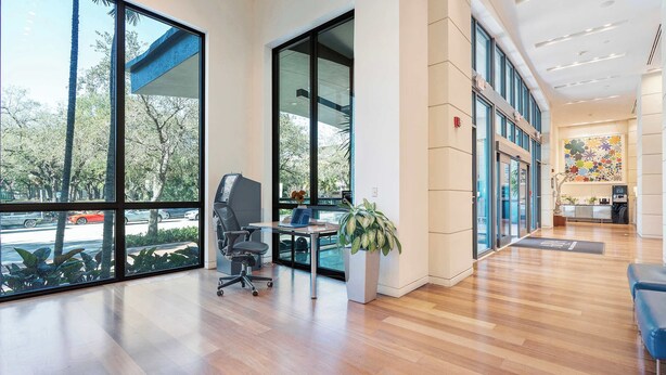 A spacious office with large windows, a reception area, and a modern interior design. - Serene Studio Suite | Prime Coconut Grove (Miami)
