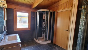 Une salle de bain avec une douche à parois de verre, un lavabo et une fenêtre.