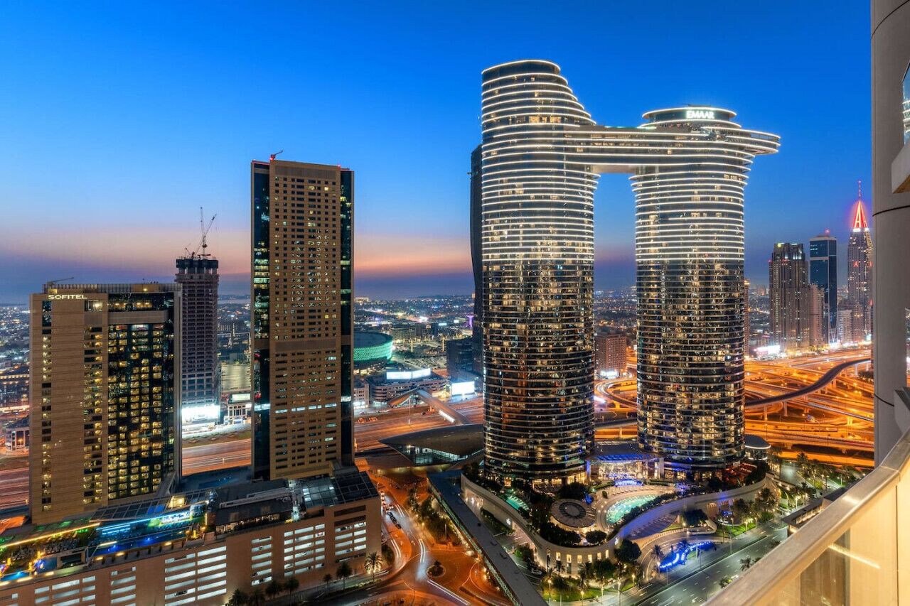 A modern high-rise hotel with a distinctive curved facade, surrounded by other tall buildings and busy roads.