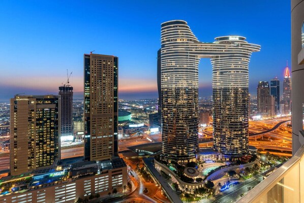 A modern high-rise hotel with a distinctive curved facade, surrounded by other tall buildings and busy roads.