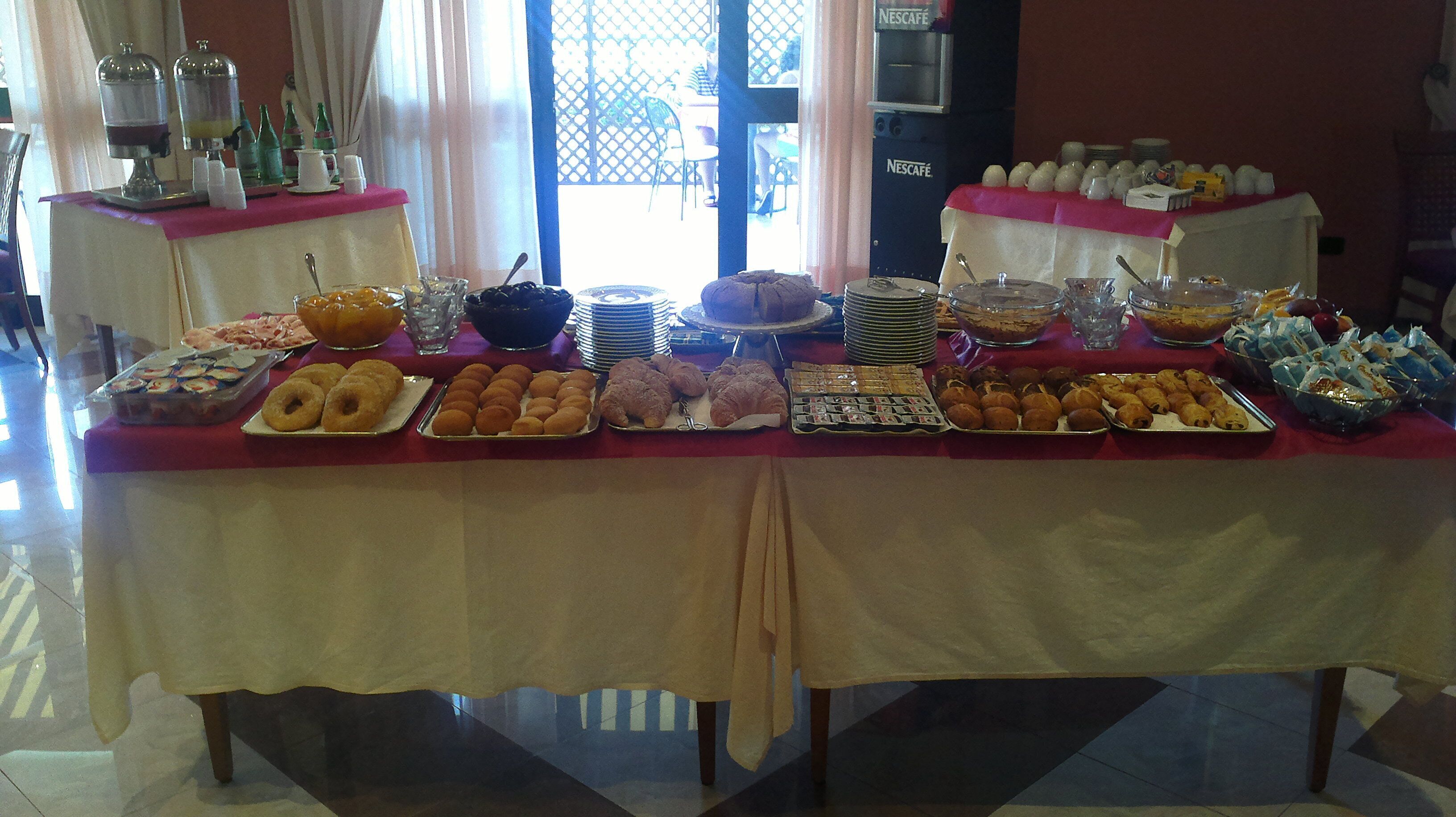 A buffet table with various food items and a Nescafe coffee machine.