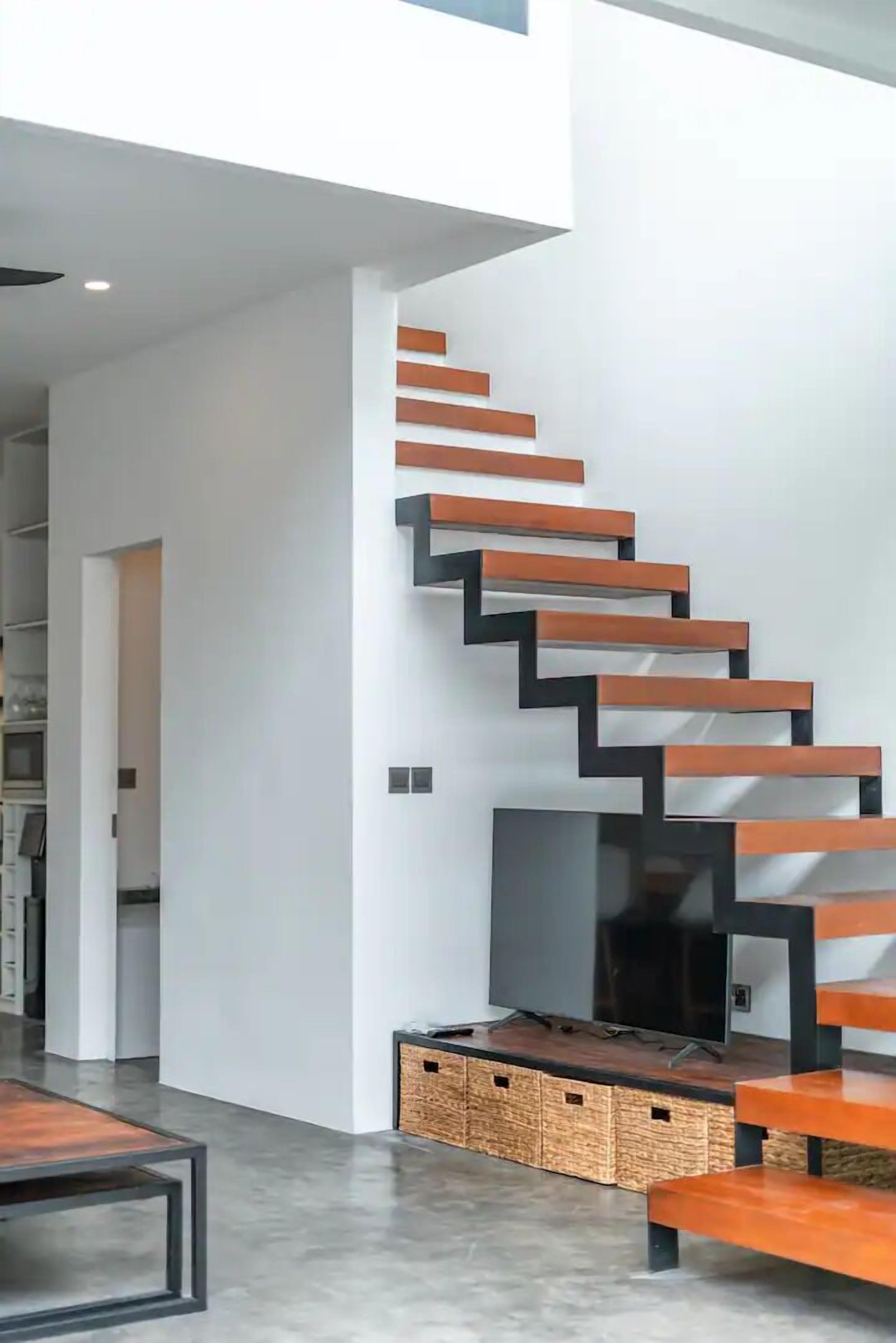 A modern interior with a staircase, a flat-screen TV, and a dining area.