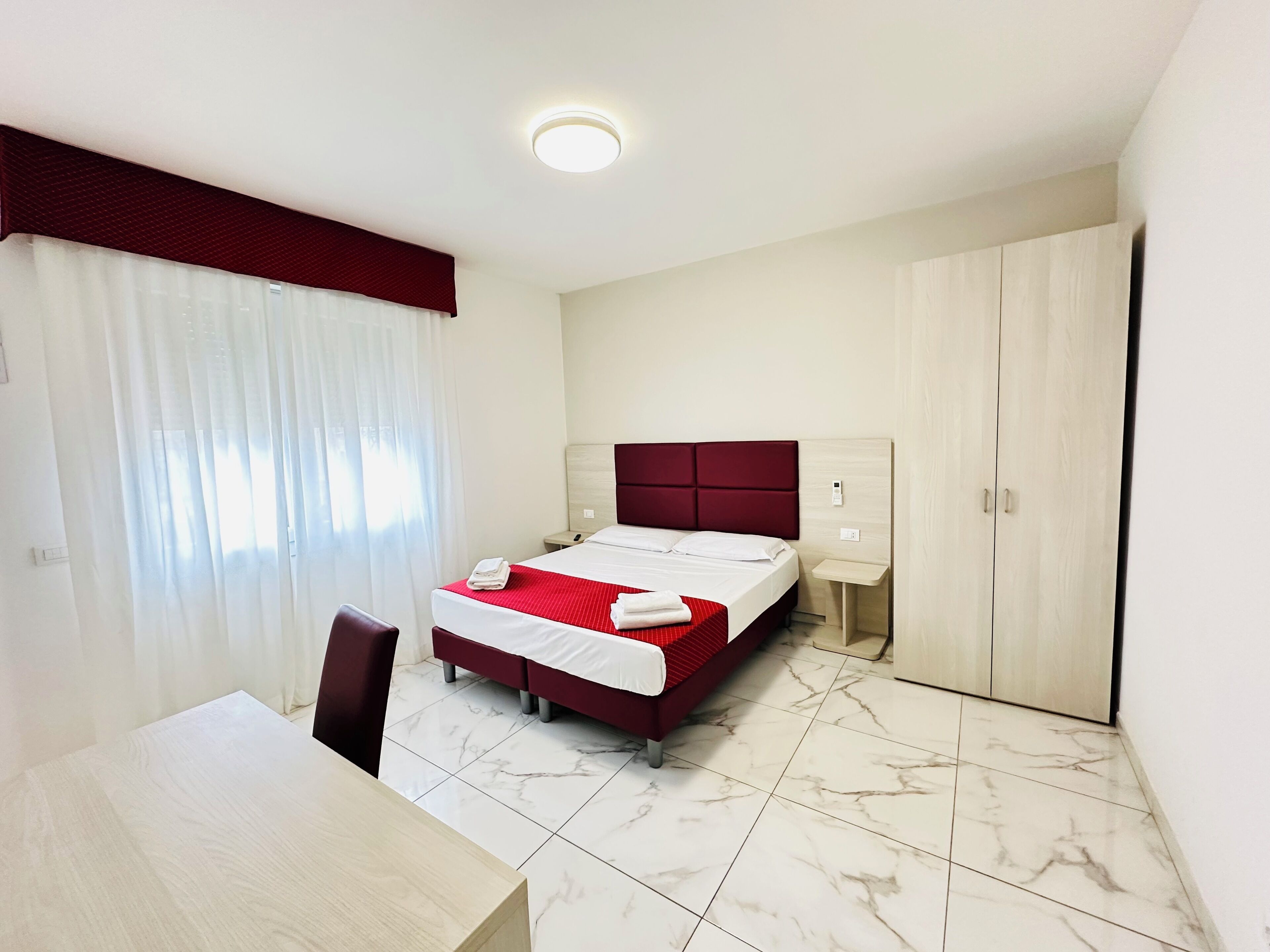 A hotel room with a bed, a desk, and a wardrobe.