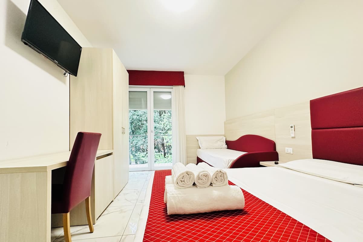 Une chambre d’hôtel équipée d’un lit, d’un bureau, d’une chaise, d’une télévision et offrant une vue sur l’extérieur.