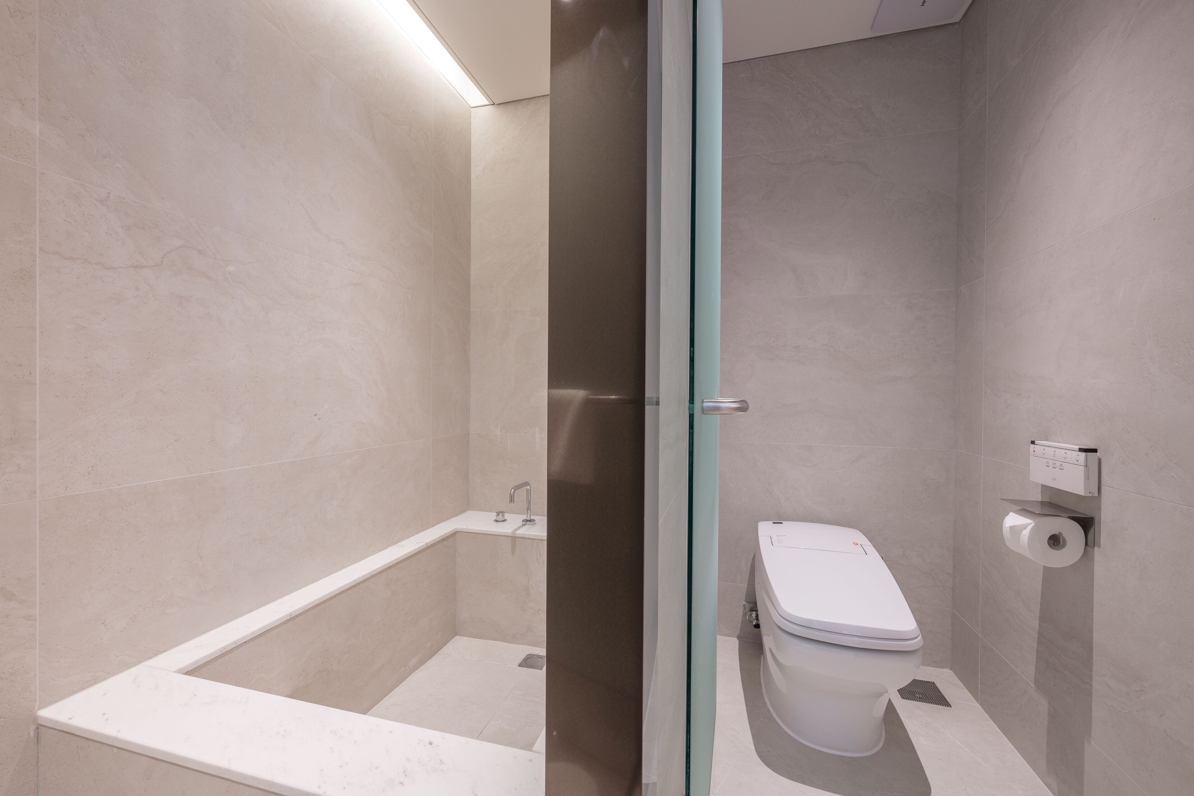 A modern bathroom with a glass-enclosed shower, a white bathtub, and a toilet.