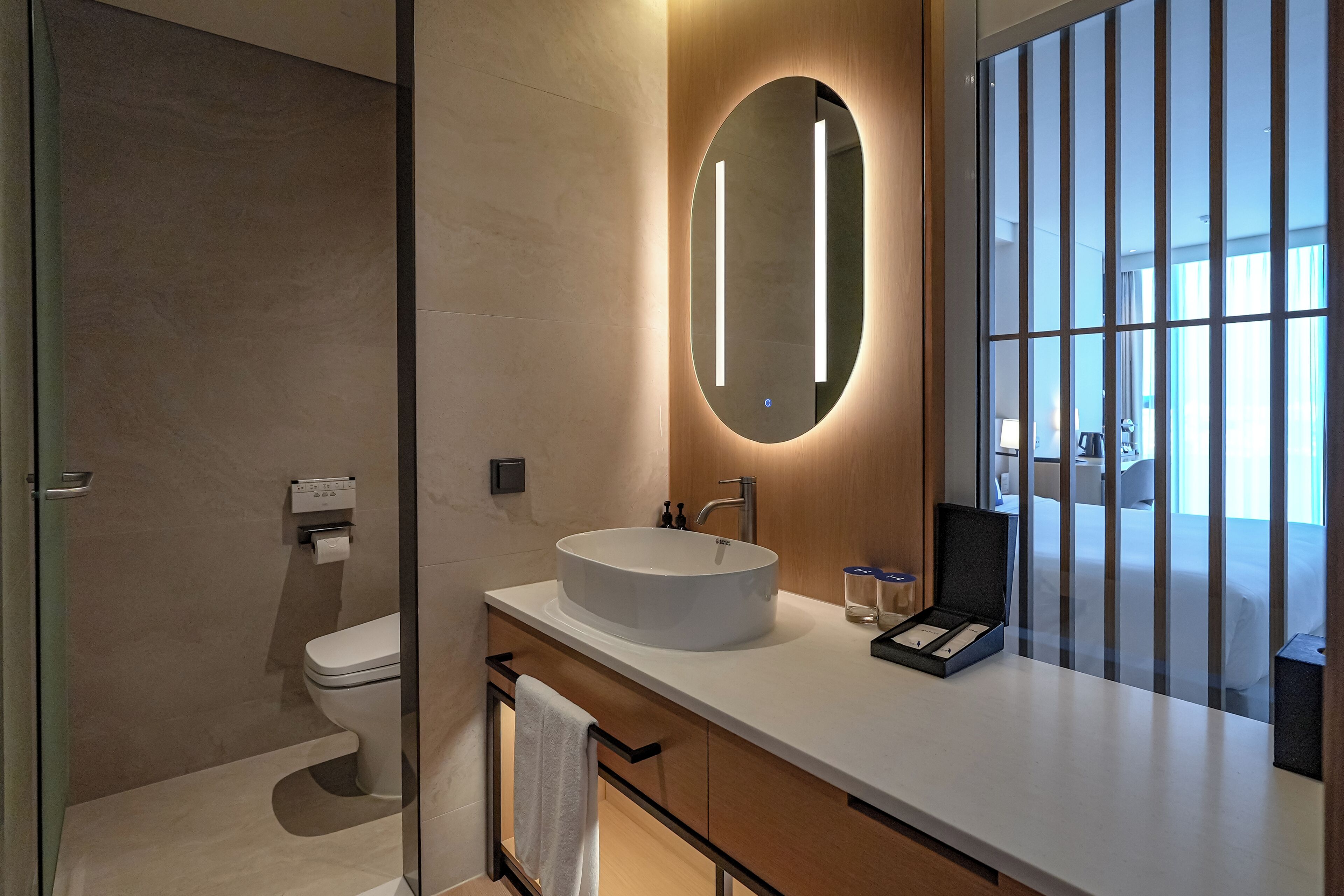 A modern bathroom with a round mirror, a white sink, and a glass shower enclosure.