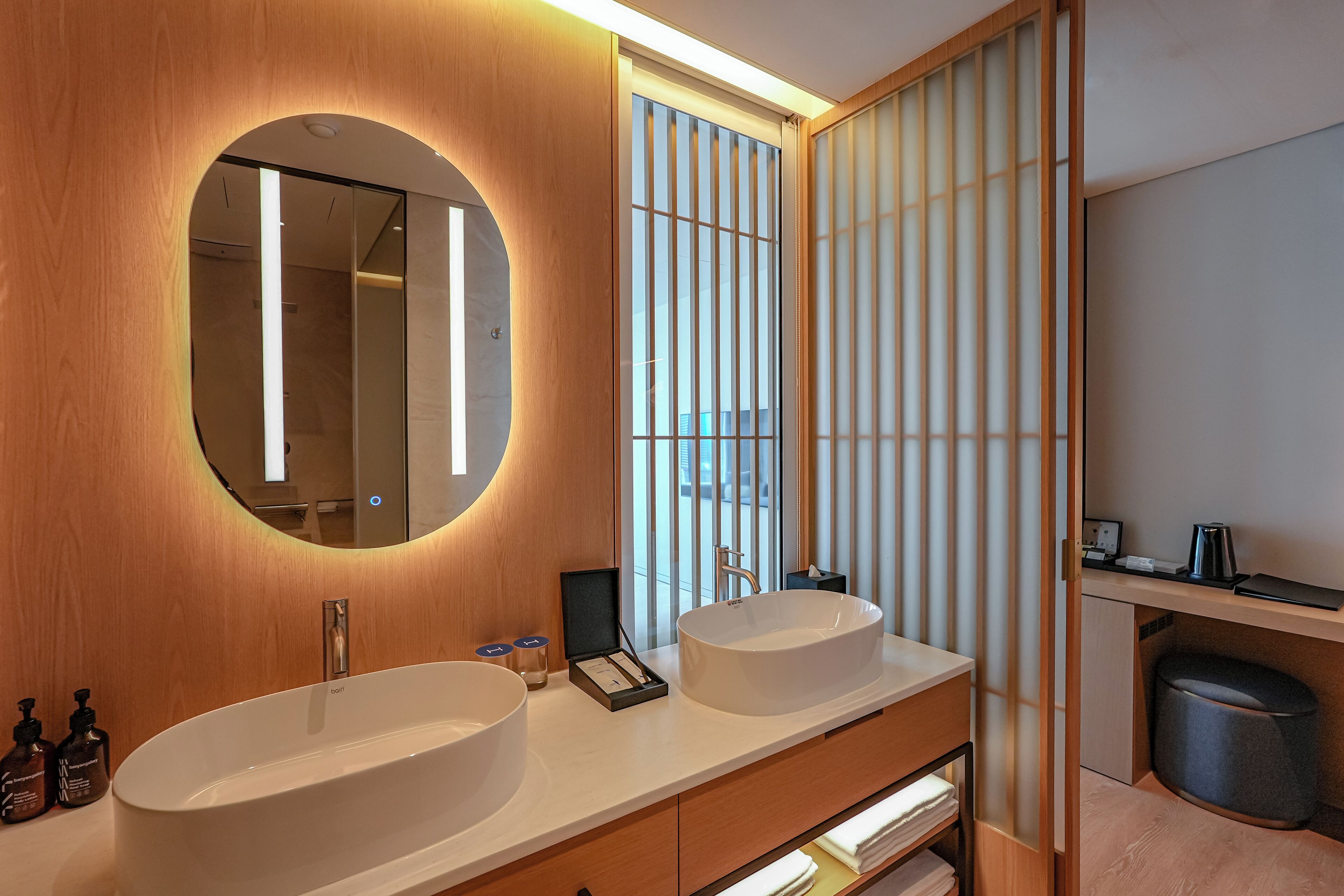 A modern bathroom with a double sink vanity, a large mirror, and a wooden vanity cabinet.