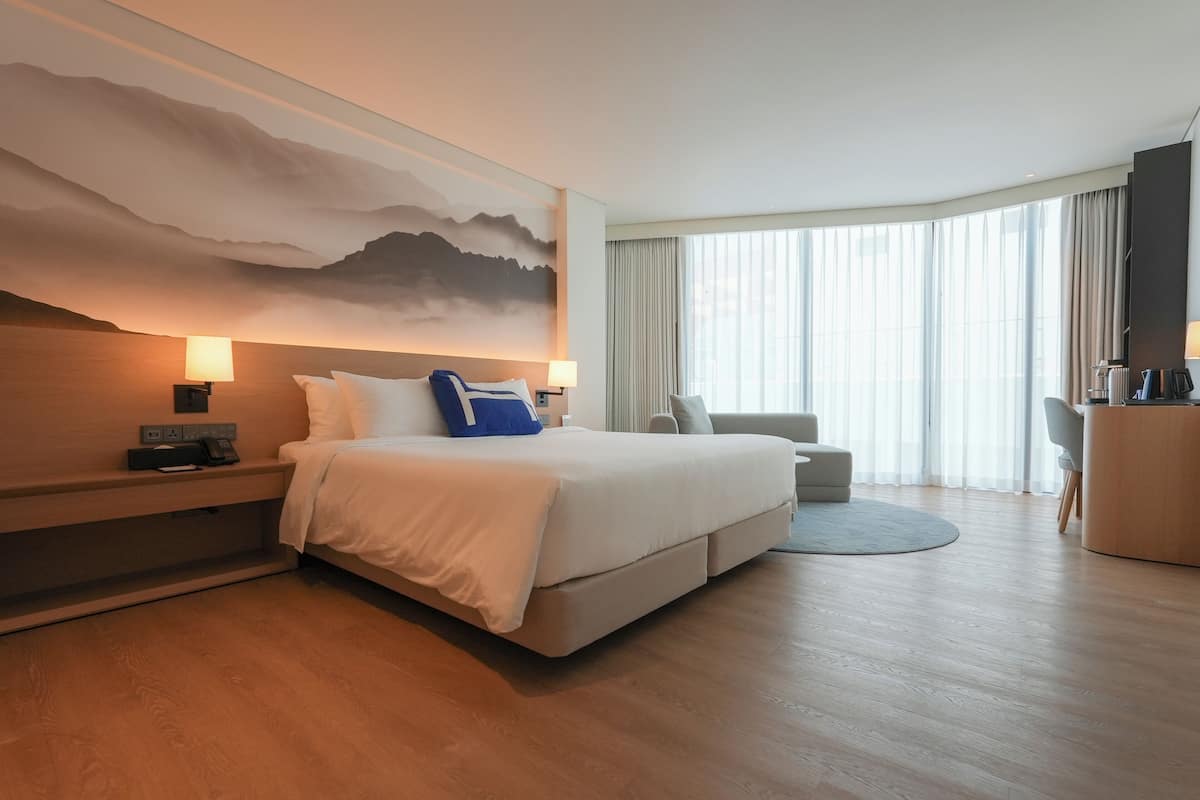 Ett modernt hotellrum med en stor säng, ett skrivbord och en sittgrupp.