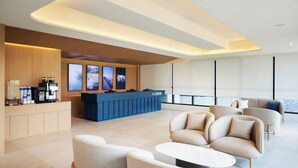 Un moderno vestíbulo de hotel con mostrador de recepción, zona de estar y grandes ventanales.
